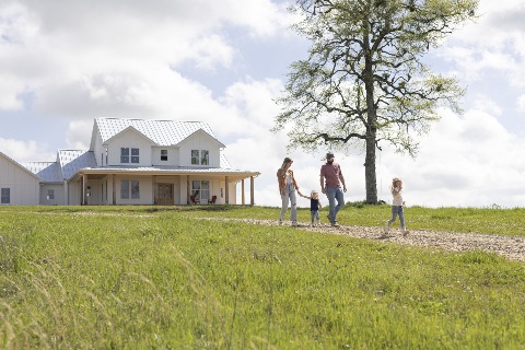 Family of four walking down the driveway with a farmhouse in the background