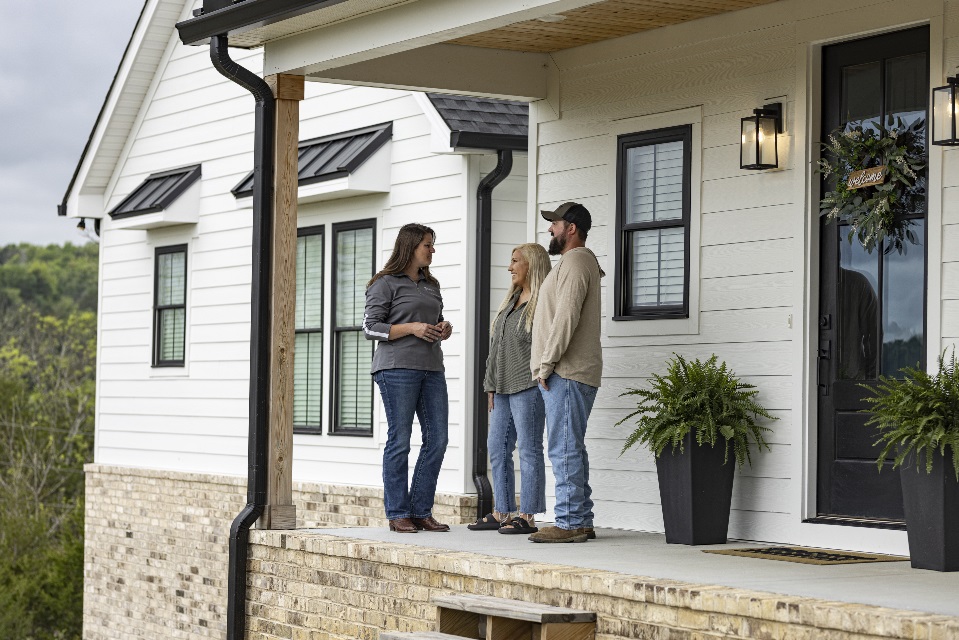 Young couple on the front porch of their new home with Rural 1st loan officer