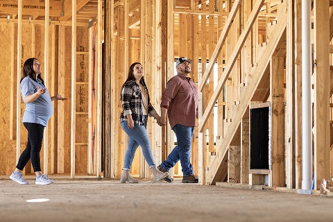 Loan officer and couple walking through a house under construction using a convertible mortgage rate.