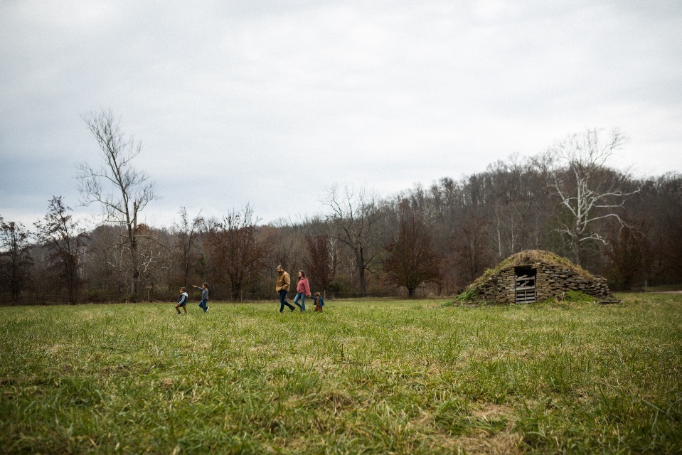 Father mother and three small children walk through open field