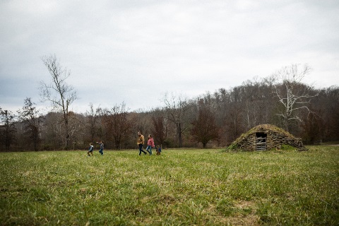 Father mother and three small children walk through open field