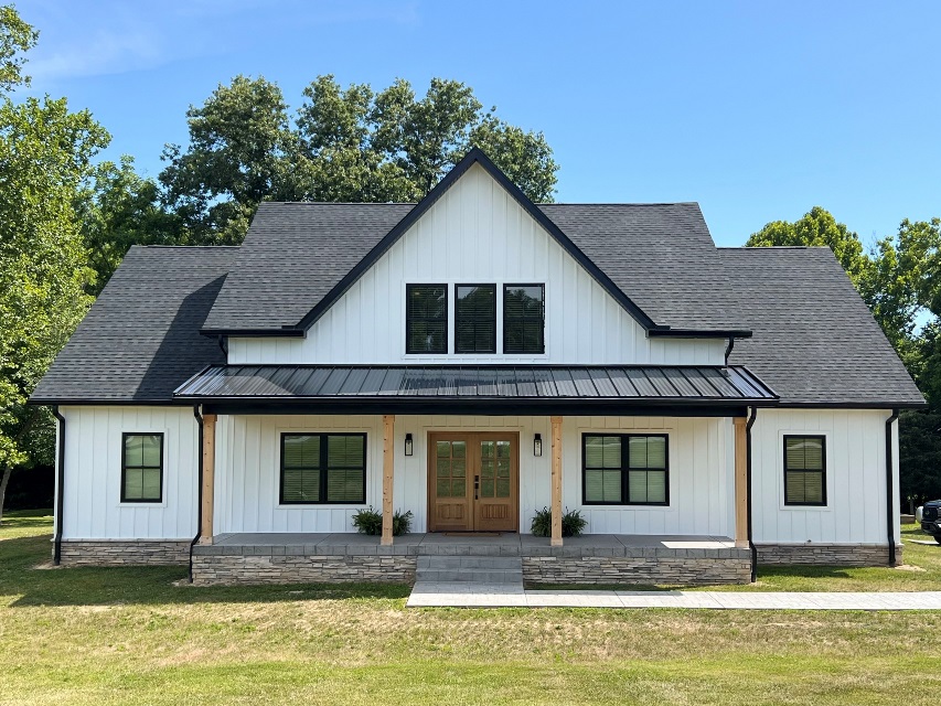 White famhouse style home with a black roof