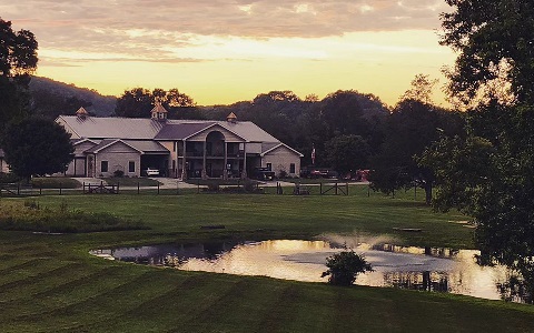 A lake in front of a rural home at sunset.