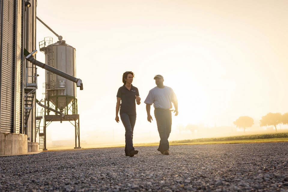 Two people walking by grain bins.