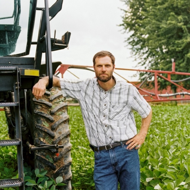 Guy stands with a sprayer.